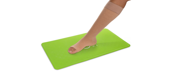 Vrouw positioneert steunkous met behulp van de Steve Mat anti-slip mat